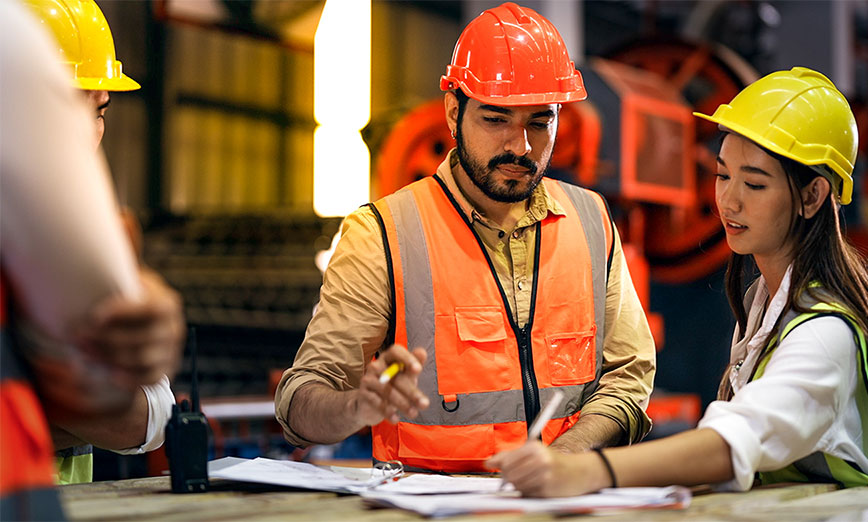 two construction workers looking at a laptop 